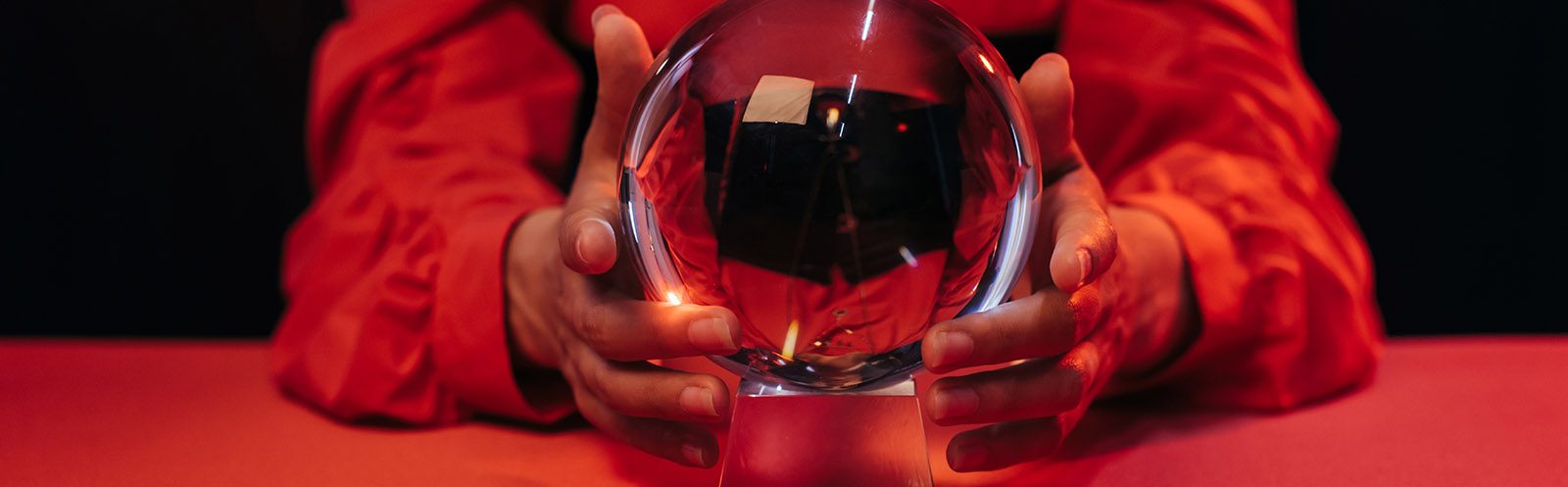 Hands holding a crystal ball against a red background